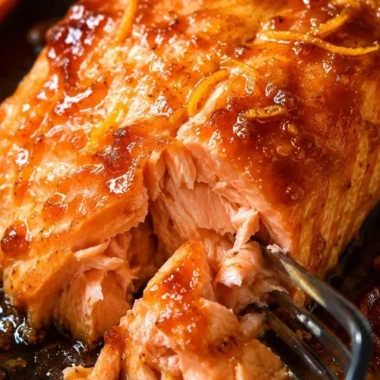 Baked salmon fillet topped with orange sauce on a serving plate