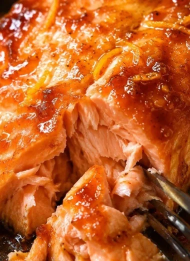 Baked salmon fillet topped with orange sauce on a serving plate