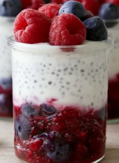 Berry and chia yogurt parfait in a clear glass, topped with fresh berries.