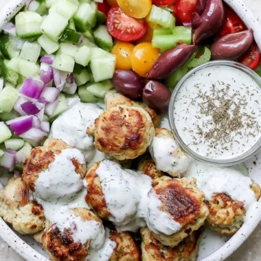 Plate of flavorful Greek chicken meatballs served with herbs and a side sauce
