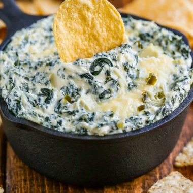 Bowl of warm and creamy spinach artichoke dip served with tortilla chips