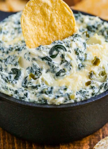 Bowl of warm and creamy spinach artichoke dip served with tortilla chips