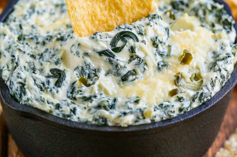 Bowl of warm and creamy spinach artichoke dip served with tortilla chips