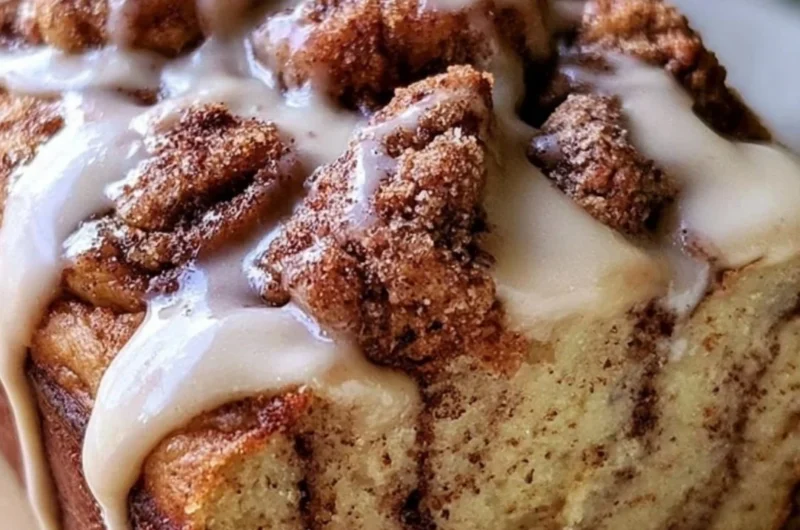 A delicious slice of cozy cinnamon roll banana bread with a cinnamon swirl topping.