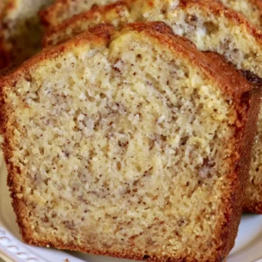 Loaf of cozy perfect banana bread on a wooden table with fresh bananas