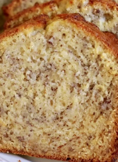 Loaf of cozy perfect banana bread on a wooden table with fresh bananas