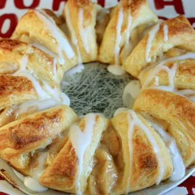 Cozy apple crescent ring served on a rustic plate with autumn leaves.