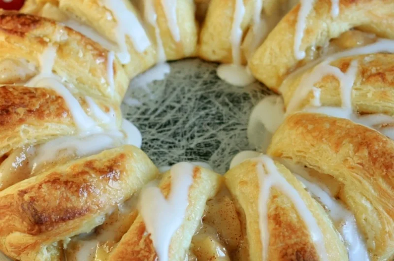 Cozy apple crescent ring served on a rustic plate with autumn leaves.