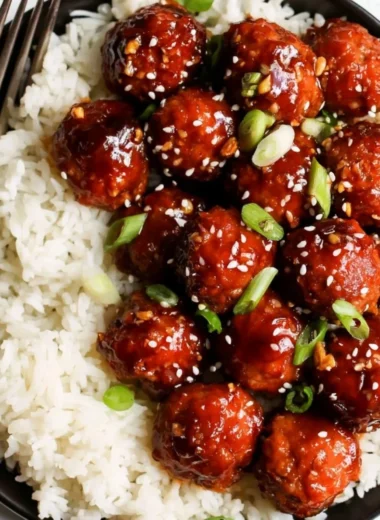 Plate of honey garlic meatballs garnished with green onions and sesame seeds
